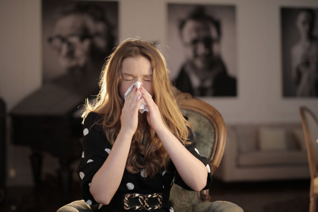 Young woman sneezing into a tissue