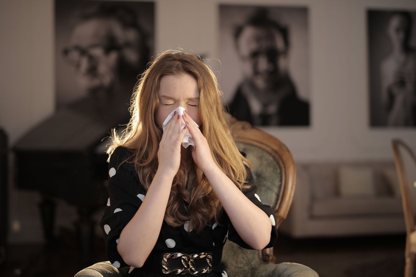 Young woman sneezing into a tissue
