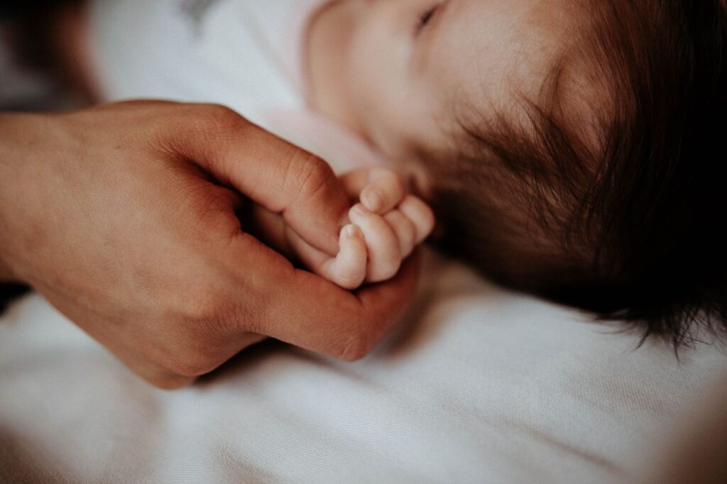 Newborn baby's hand held by a parent
